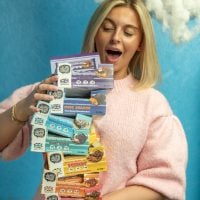 woman holding a stack of yubi bar protein bars